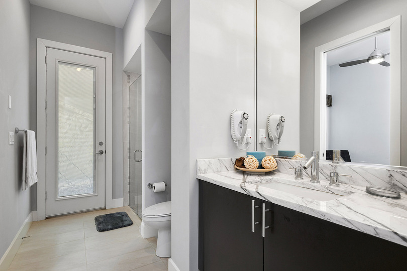 The en-suite bathroom features a glass door walk-in shower, marble vanity, and access door from the hallway