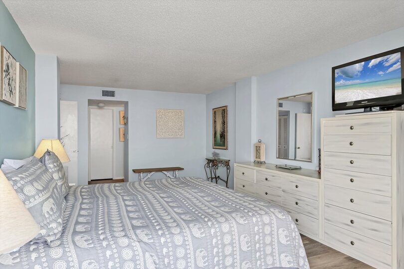 Primary Bedroom with king bed, en suite, balcony access, and a 32" TV