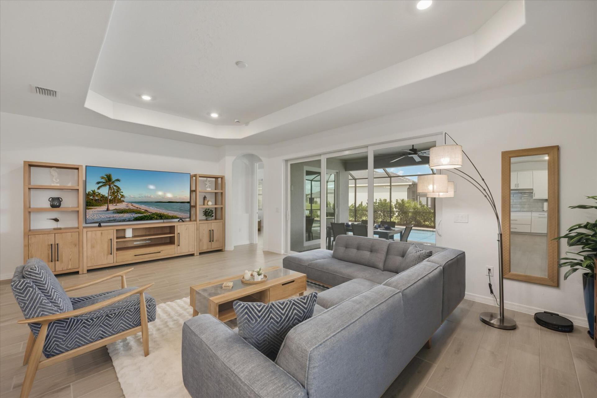 Living room overlooking the sparkling pool. Features ample seating and 85-inch Smart TV