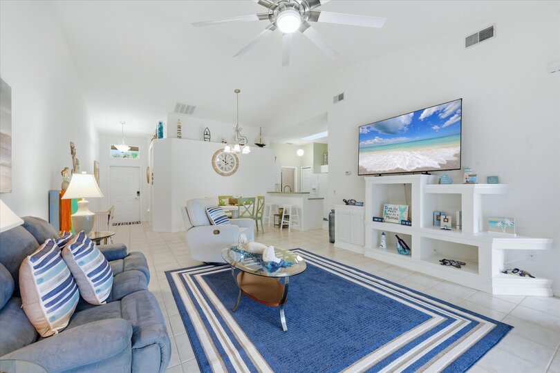 Large living space includes patio access overlooking the pond, and 75-inch Smart TV
