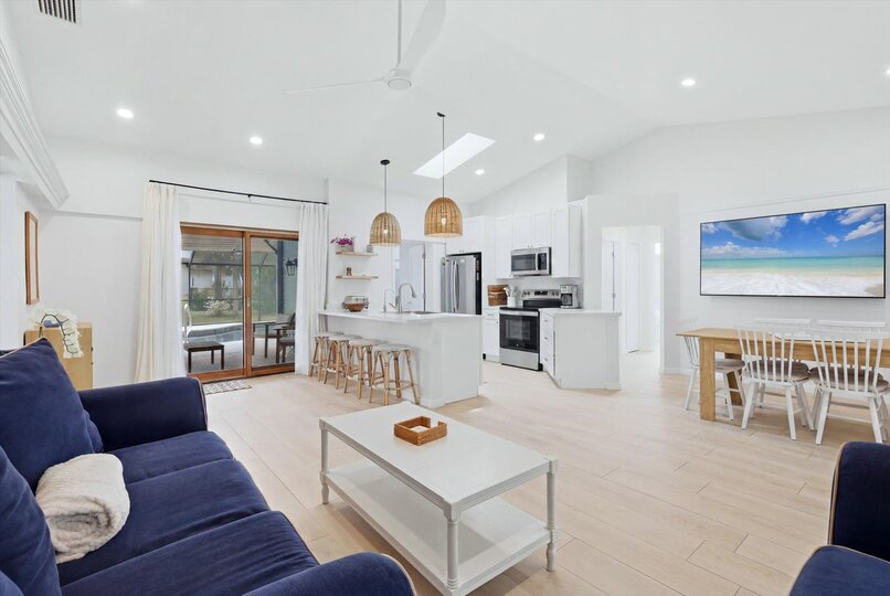Bright, open living space with comfy seating, 75-inch Smart TV, and lanai access